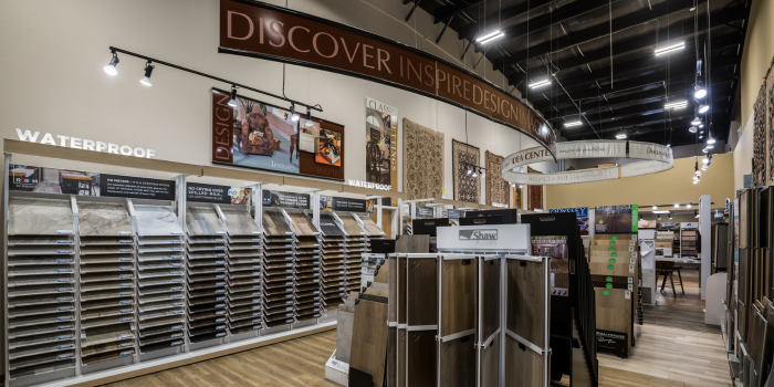 Flooring store with waterproof wood look flooring samples on display wall.